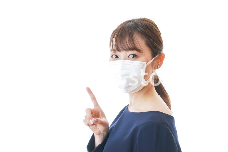 マスクを装着して指を指す若い女性