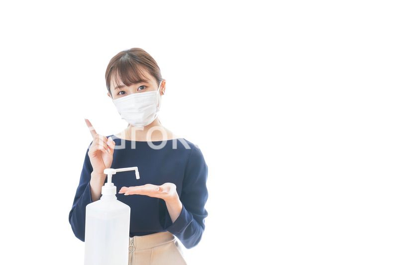 OKサインをしながらアルコール消毒をする若い女性