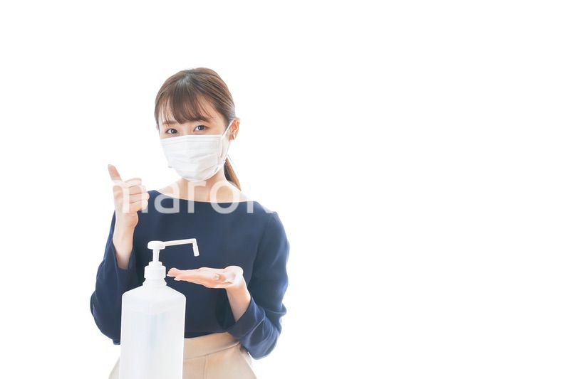 OKサインをしながらアルコール消毒をする若い女性