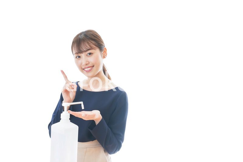 OKサインをしながらアルコール消毒をする若い女性