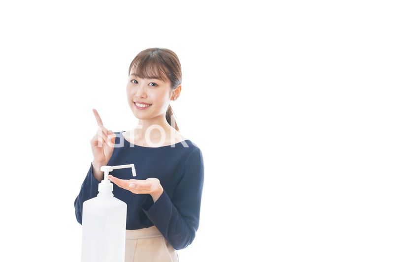 OKサインをしながらアルコール消毒をする若い女性
