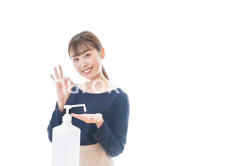 OKサインをしながらアルコール消毒をする若い女性