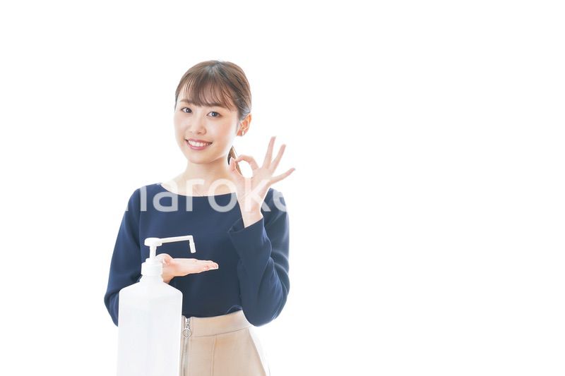 OKサインをしながらアルコール消毒をする若い女性