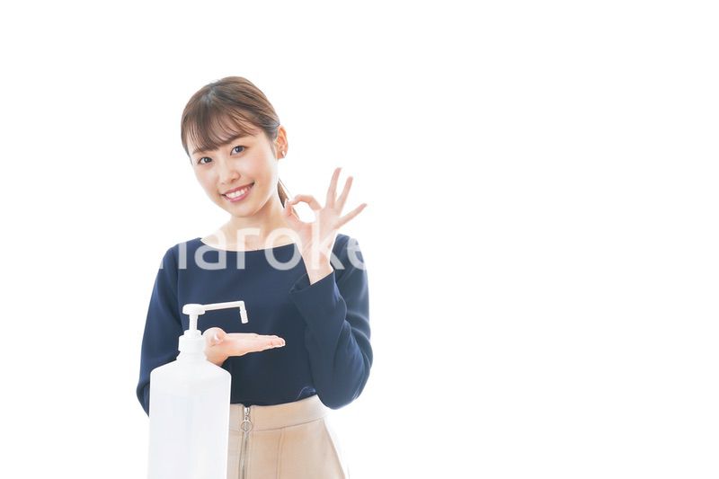 OKサインをしながらアルコール消毒をする若い女性