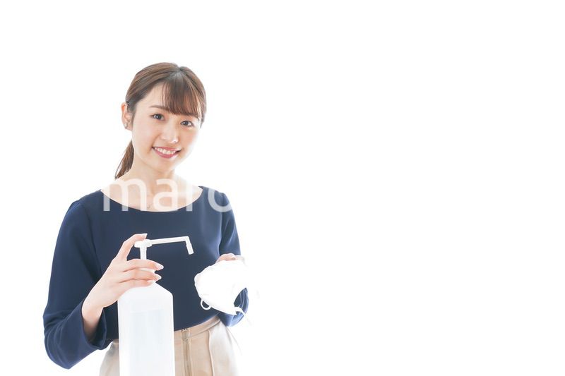 マスクをアルコール消毒する若い女性