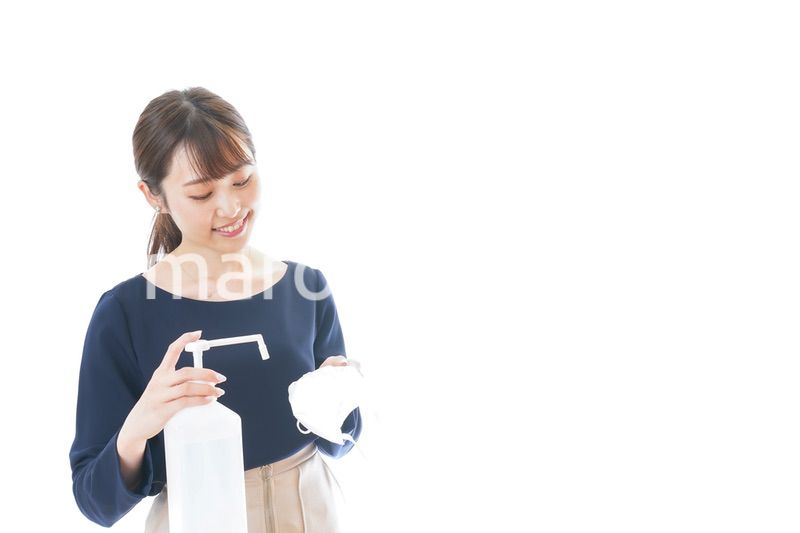 マスクをアルコール消毒する若い女性