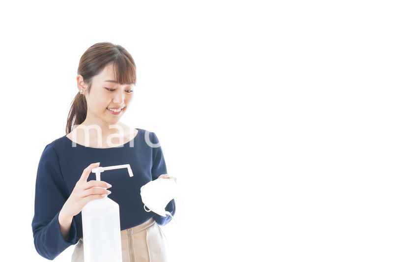 マスクをアルコール消毒する若い女性