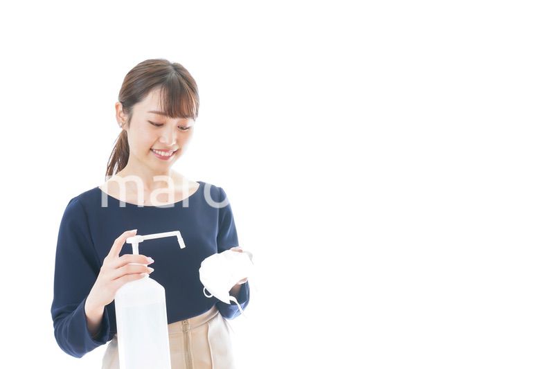 マスクをアルコール消毒する若い女性