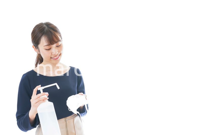 マスクをアルコール消毒する若い女性