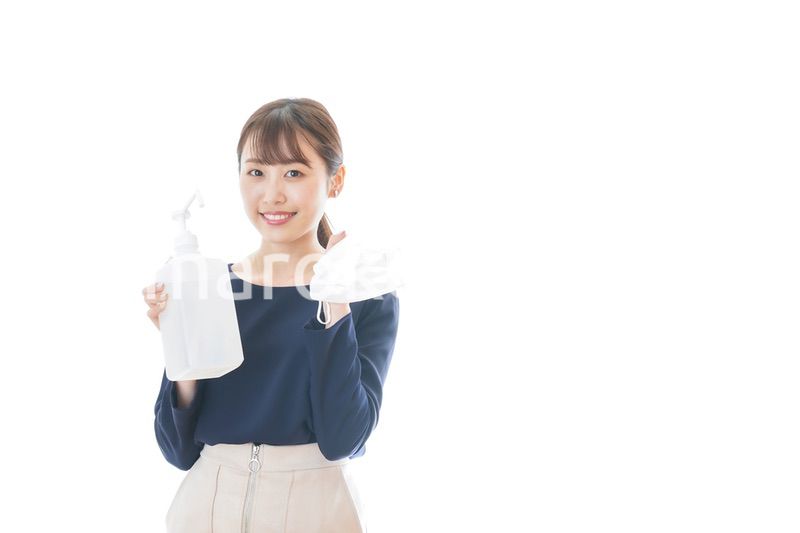 マスクとアルコール消毒液を持つ若い女性