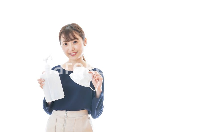 マスクとアルコール消毒液を持つ若い女性