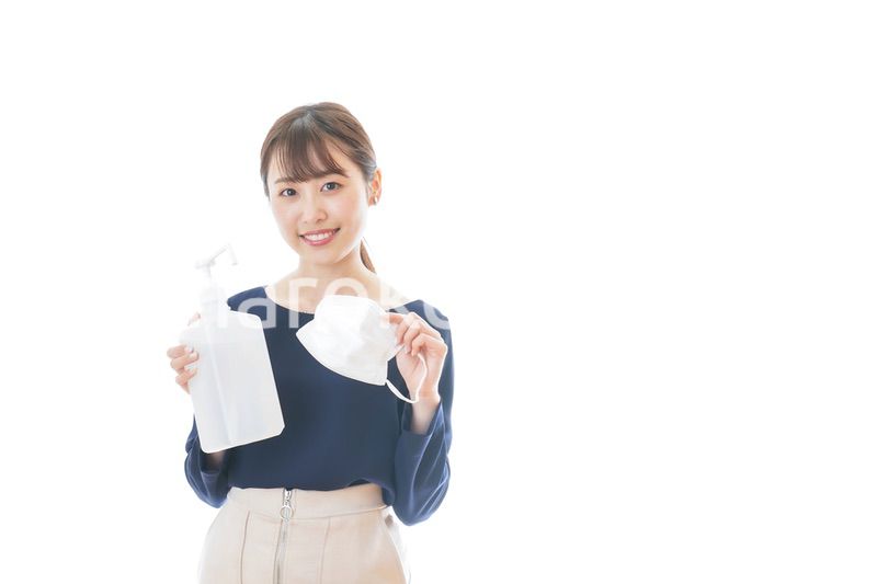 マスクとアルコール消毒液を持つ若い女性
