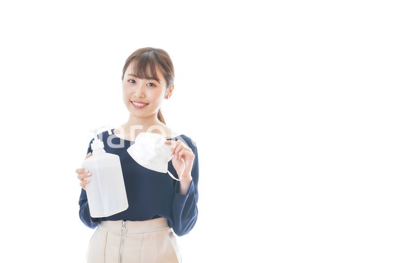 マスクとアルコール消毒液を持つ若い女性