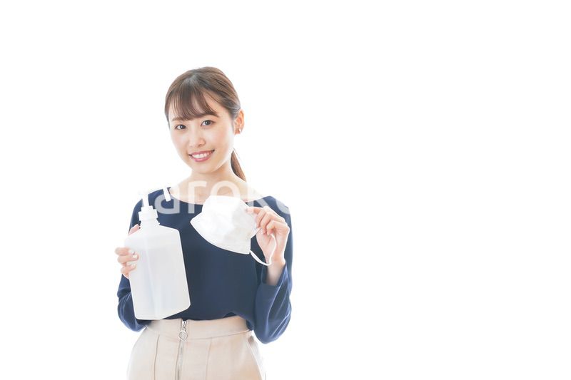 マスクとアルコール消毒液を持つ若い女性