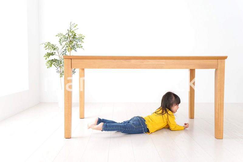 机の下に避難する子ども