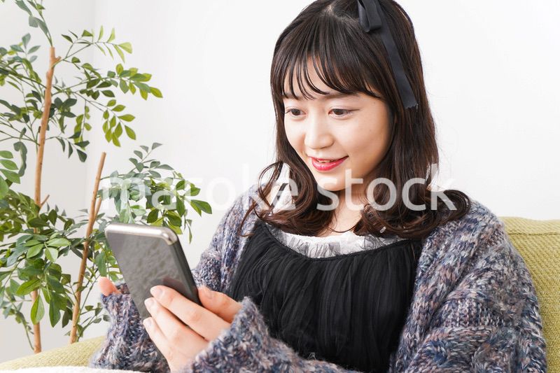 家でスマートフォンを使う若い女性