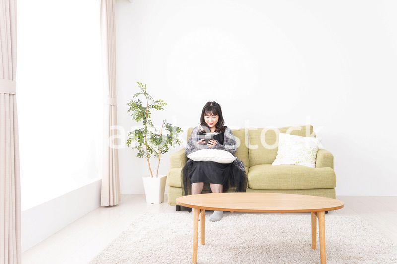 家でスマートフォンを使う若い女性