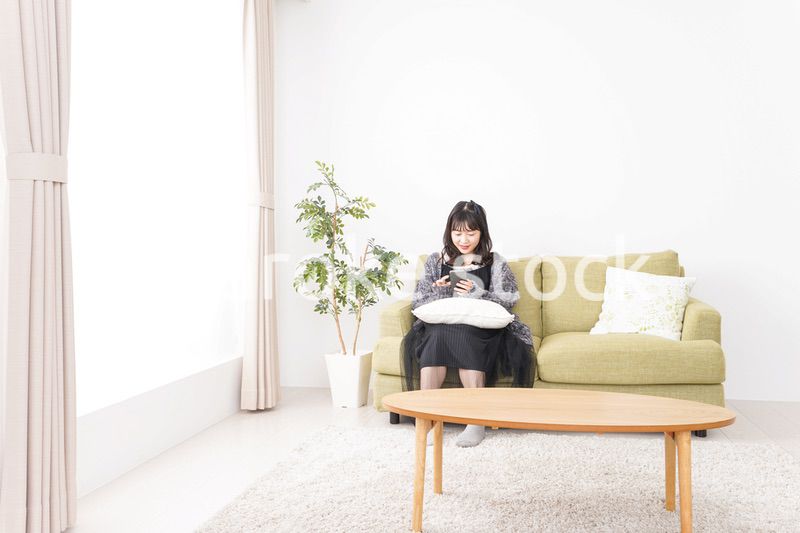 家でスマートフォンを使う若い女性