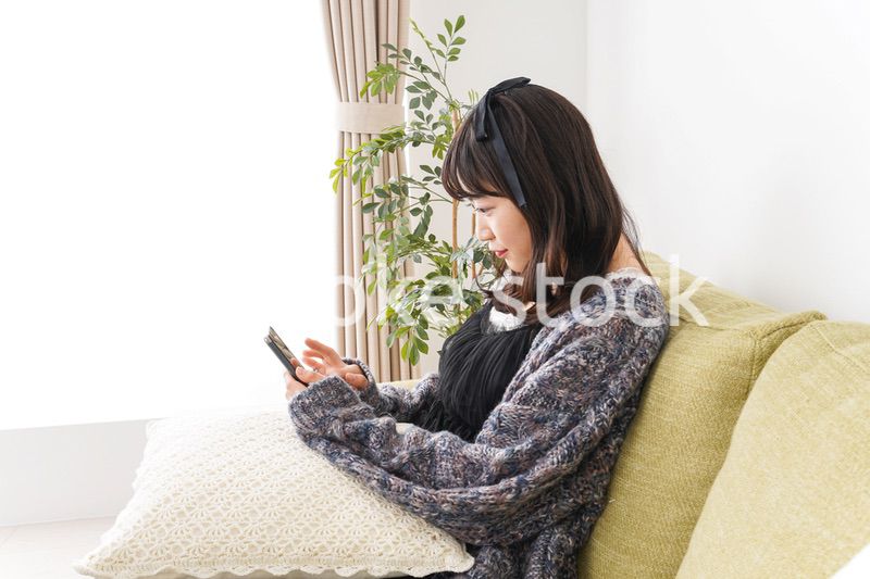 家でスマートフォンを使う若い女性