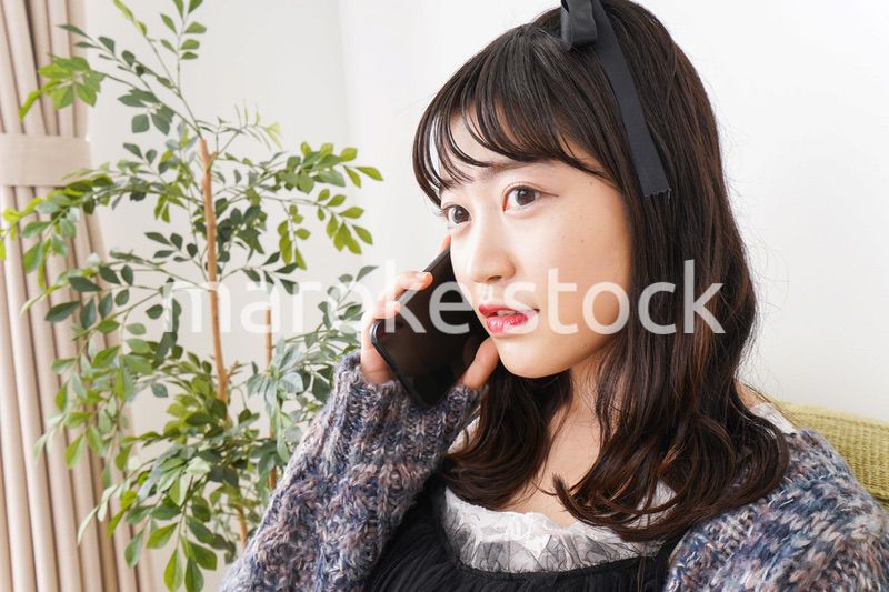 家でスマートフォンを使う若い女性