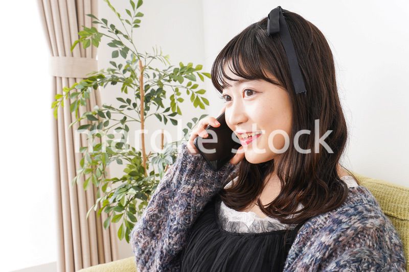 家でスマートフォンを使う若い女性