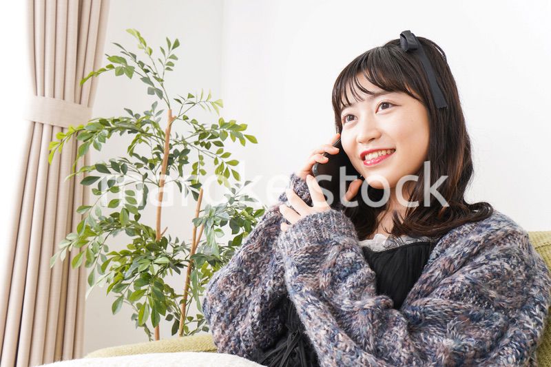 家でスマートフォンを使う若い女性