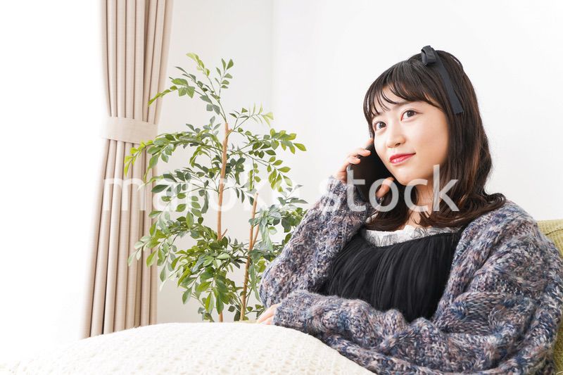 家でスマートフォンを使う若い女性