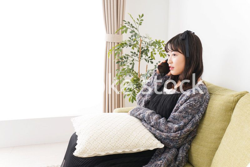 家でスマートフォンを使う若い女性