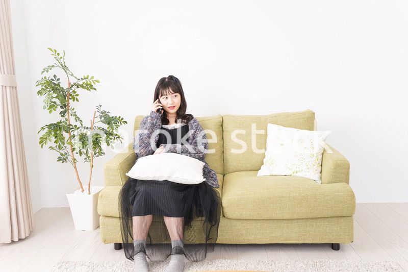 家でスマートフォンを使う若い女性