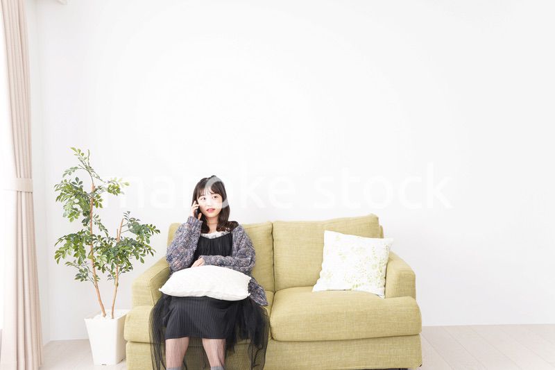 家でスマートフォンを使う若い女性