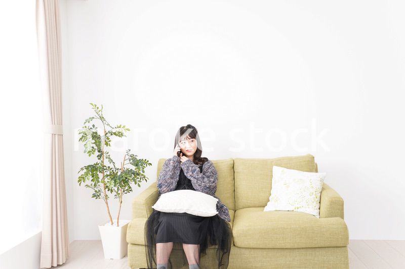 家でスマートフォンを使う若い女性