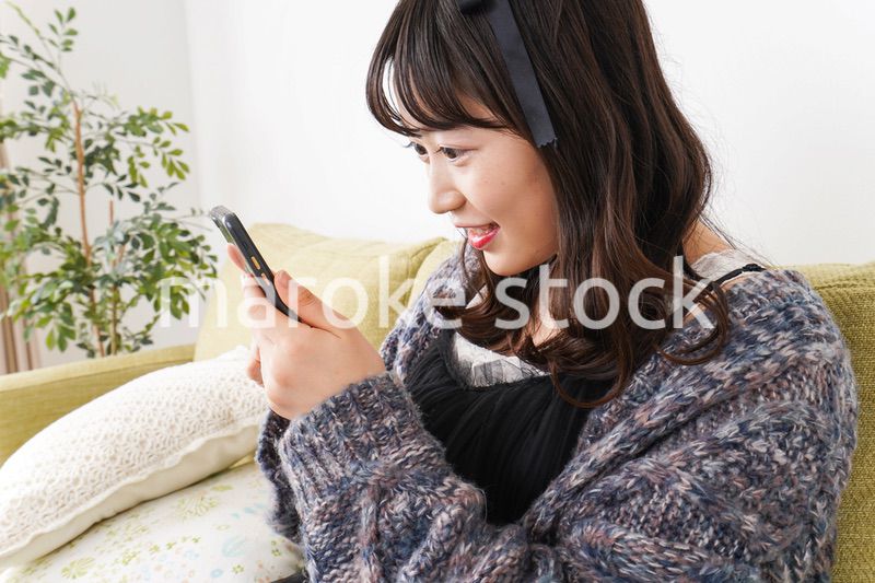 家でスマートフォンを使う若い女性