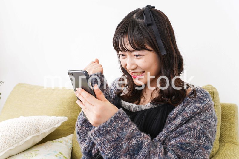 家でスマートフォンを使う若い女性