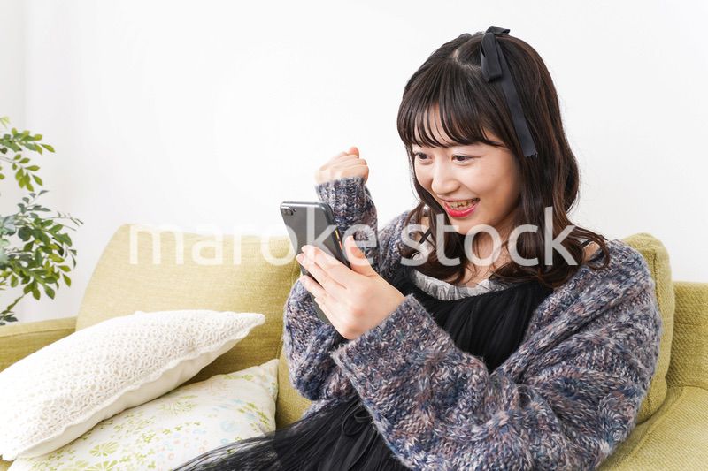 家でスマートフォンを使う若い女性