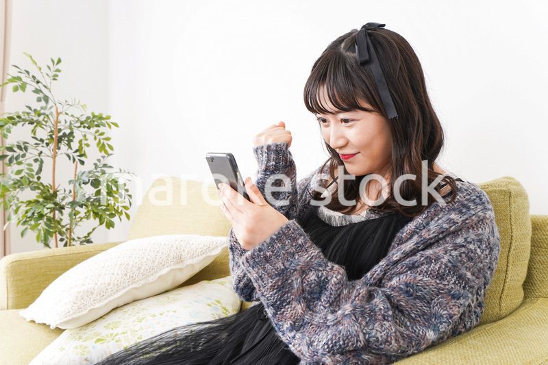 家でスマートフォンを使う若い女性