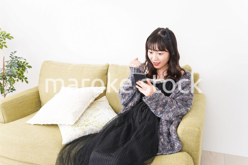 家でスマートフォンを使う若い女性