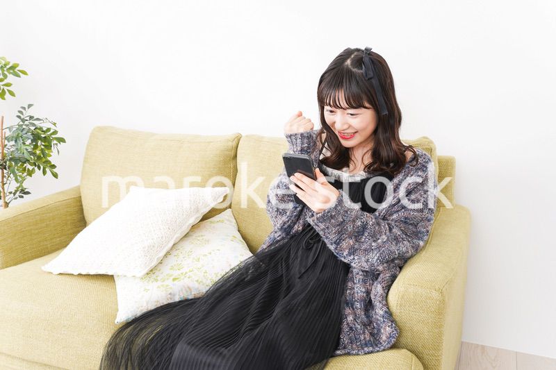 家でスマートフォンを使う若い女性