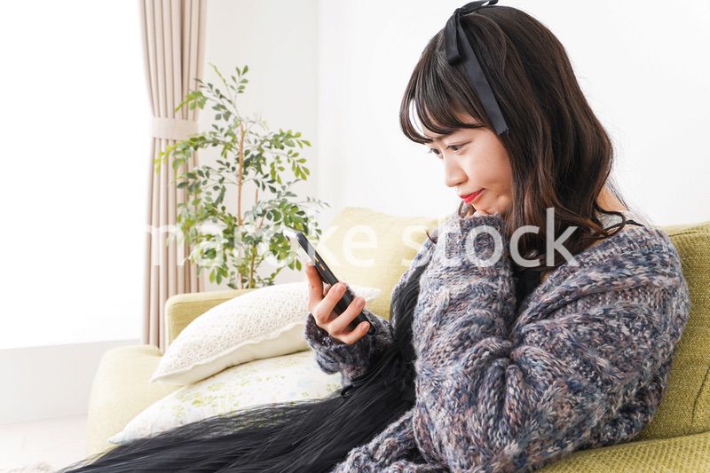 家でスマートフォンを使う若い女性