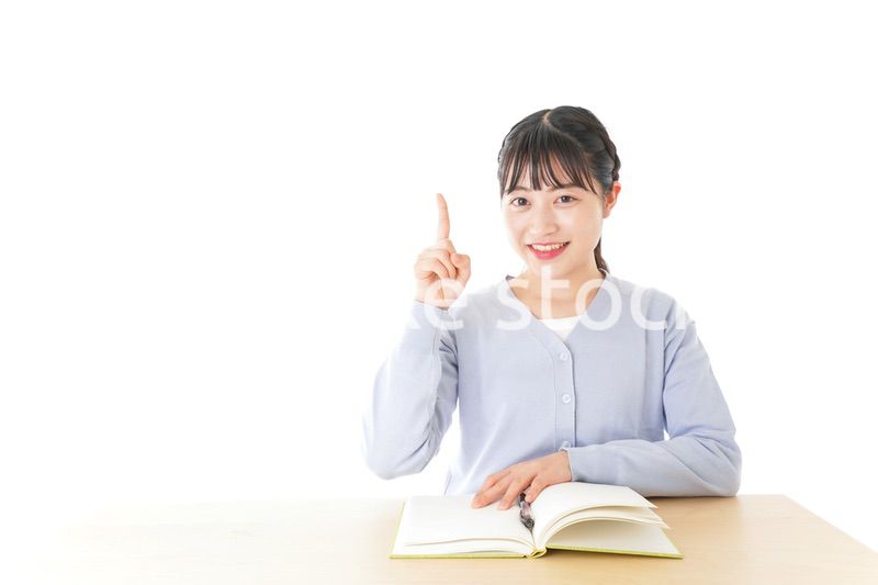 勉強をしながら指を指す若い女子学生