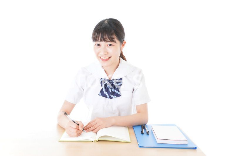 机で勉強をする制服姿の女子学生