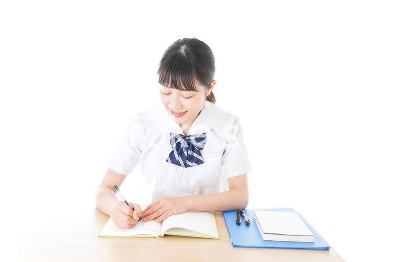 机で勉強をする制服姿の女子学生