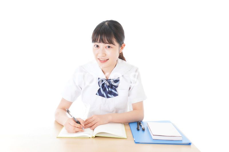 机で勉強をする制服姿の女子学生