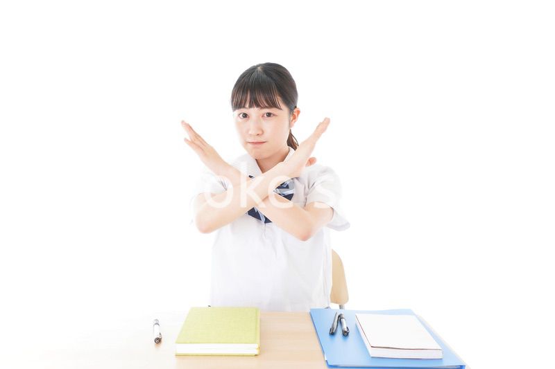 バツを示す制服姿の女子学生