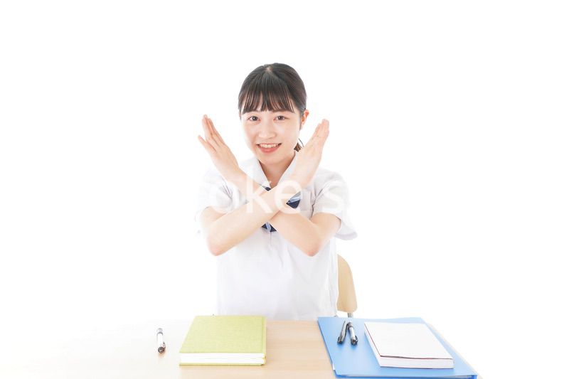 バツを示す制服姿の女子学生