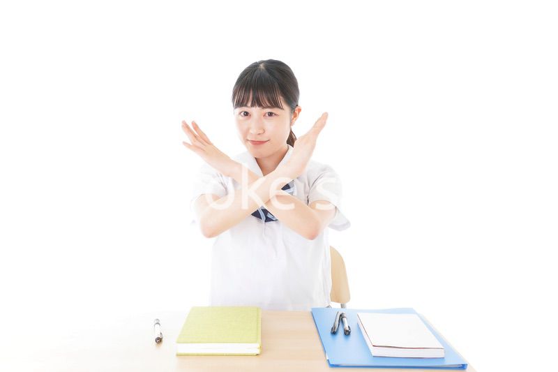 バツを示す制服姿の女子学生