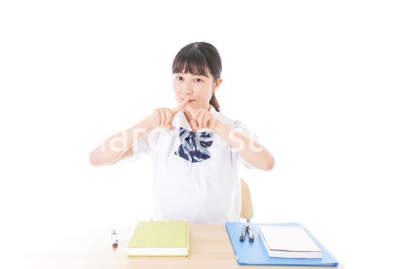 バツを示す制服姿の女子学生