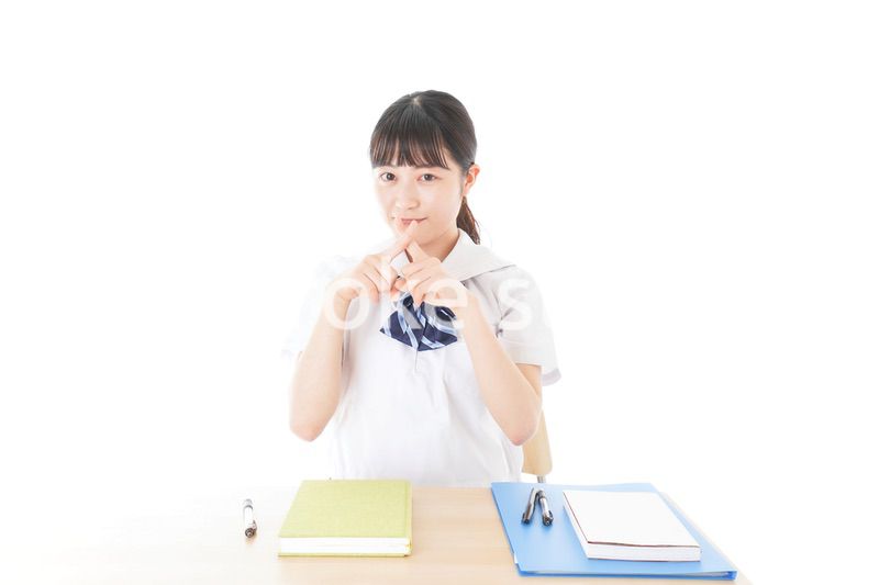 バツを示す制服姿の女子学生