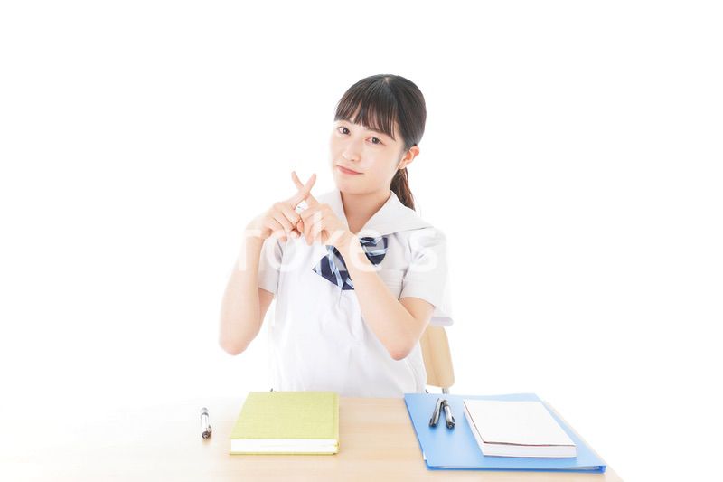 バツを示す制服姿の女子学生