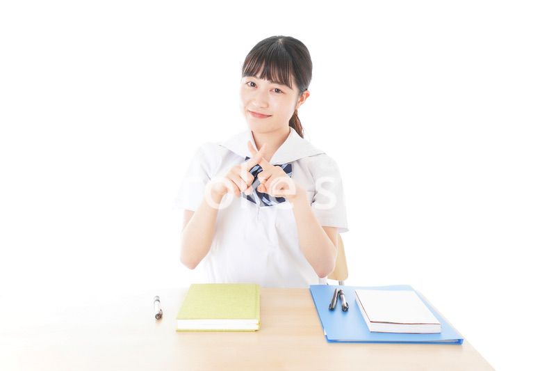 バツを示す制服姿の女子学生