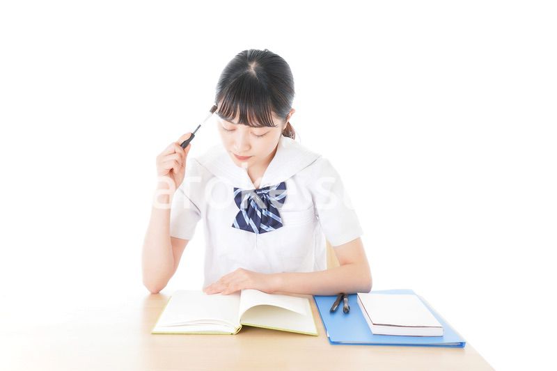 机で勉強をする制服姿の女子学生